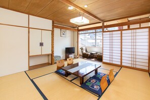 Una habitación japonesa tradicional con suelo de tatami, una mesa de madera baja y puertas correderas.