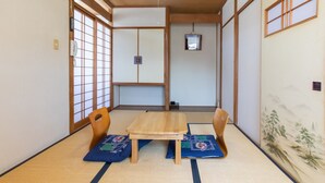 Um quarto japonês tradicional com tatames, uma mesa de madeira e duas cadeiras.