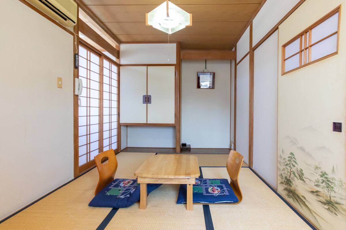 Et traditionelt japansk rum med tatamimåtter, et træbord og to stole.