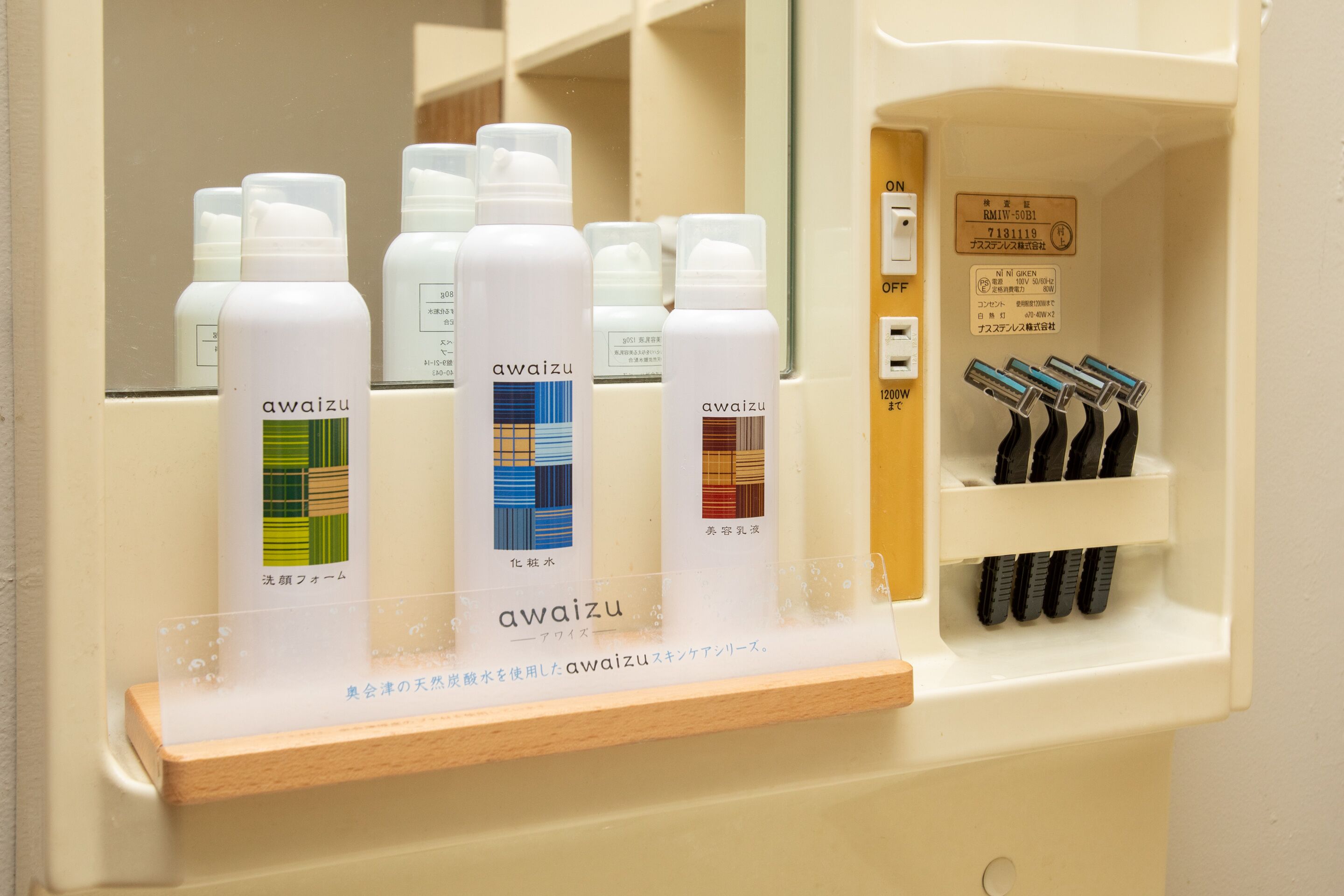Une étagère de salle de bain avec plusieurs bouteilles de produits de la marque Awaizu, un support à rasoir et un miroir.