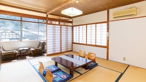 Um quarto japonês tradicional com tatames, uma mesa baixa e assentos.