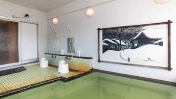 A spa area with a green-tiled floor, a large painting of a snowy landscape, and a mirror above the sink.