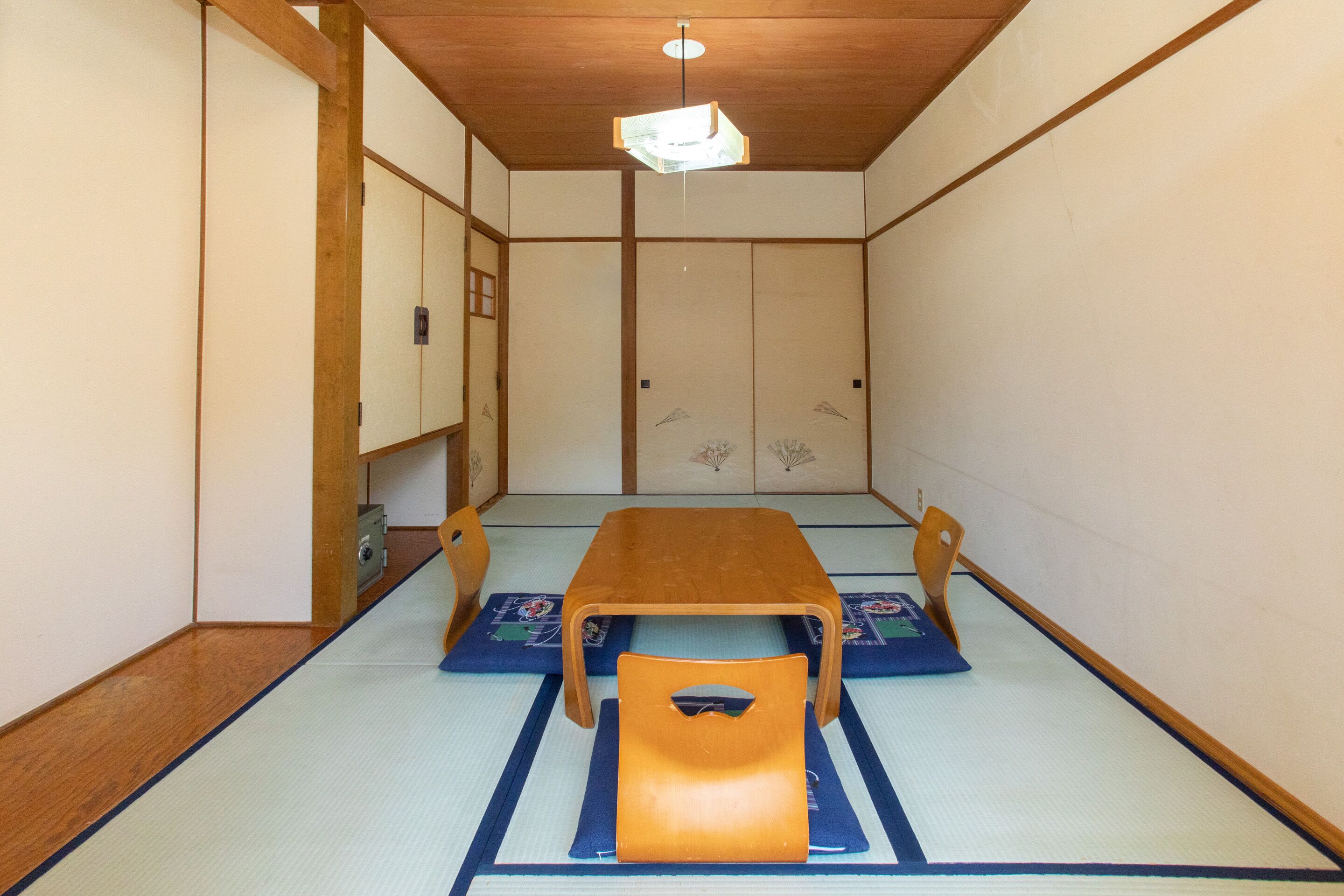 Una tradizionale stanza giapponese con pavimento in tatami, un tavolo di legno e una poltrona arancione bassa.