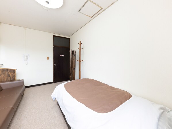 Una habitación de hotel con una cama, un sofá, un perchero y una puerta.