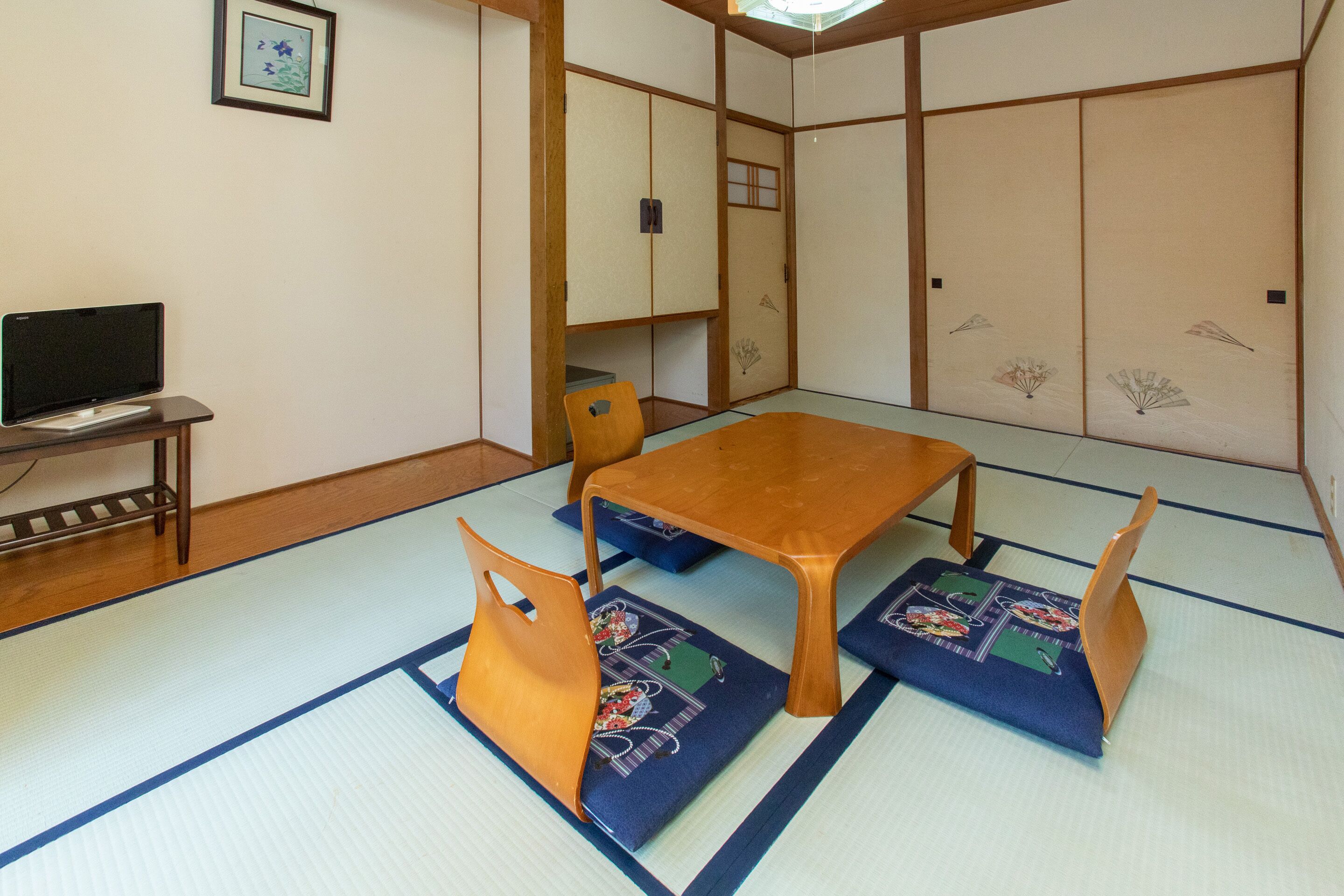 A traditional Japanese room with tatami flooring, a low wooden table, and matching cushions.