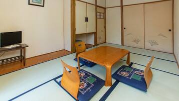 A traditional Japanese room with tatami flooring, a low wooden table, and matching cushions.