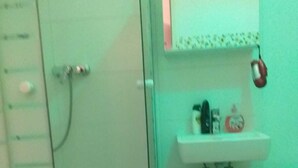 A bathroom with a glass shower enclosure, a sink, and a trash can. - Ferienwohnung) (Wien)