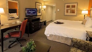A hotel room with a bed, desk, chair, television, and a mirror.