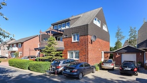 A residential building with a brick facade, multiple windows, and a satellite dish. There are three cars parked in the driveway. - Single room in the Hotel-Pension Marlies - Single room (Neuharlingersiel)
