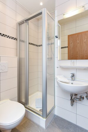 Een douche, handdoeken, zeep, toiletpapier