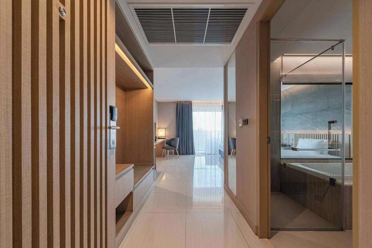 Una habitación de hotel moderna con baño, un escritorio con silla y una cama con cabina de ducha de vidrio.