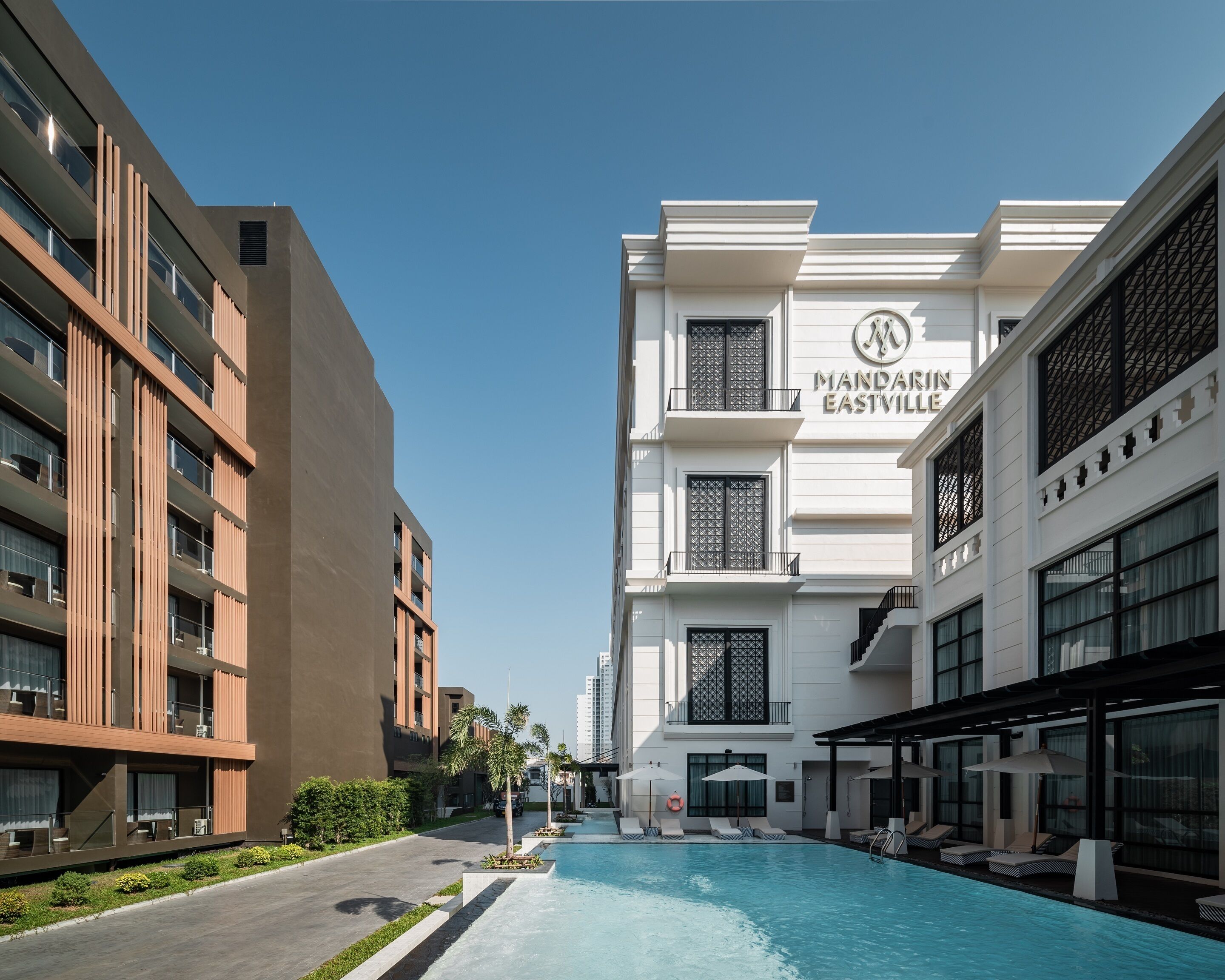 A modern hotel with a swimming pool, outdoor seating, and a clear view of the building's facade.