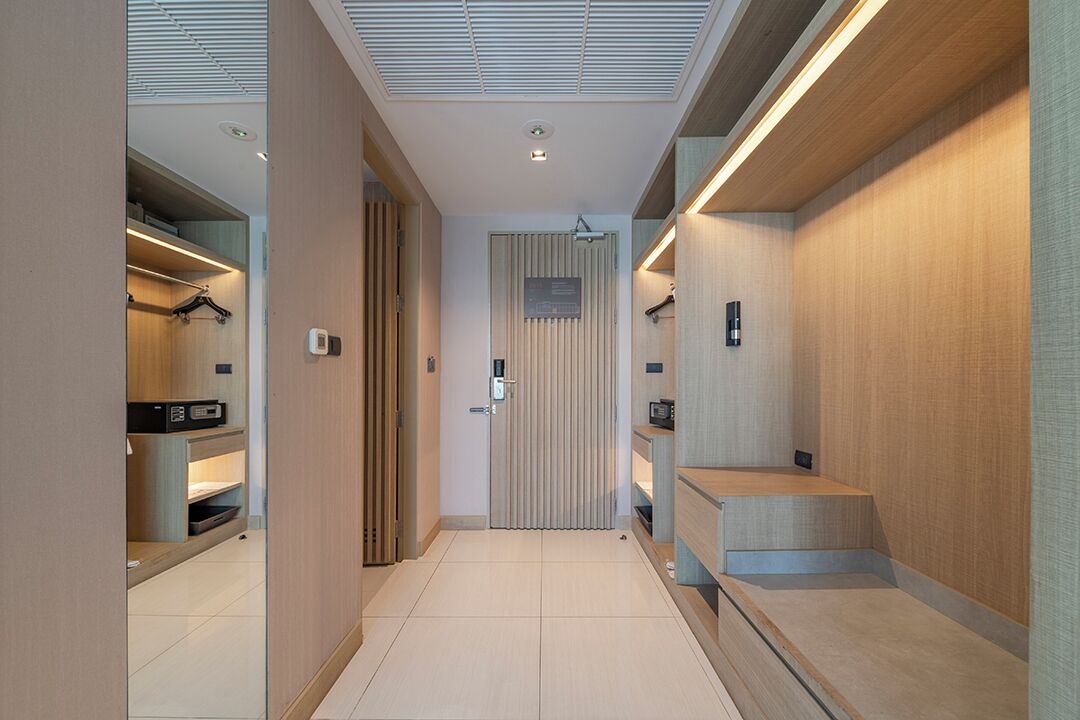 Un pasillo moderno con puerta de madera, estanterías empotradas y un banco.