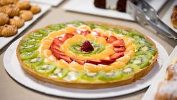 A fruit tart on a white plate with a lace doily underneath.