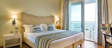 A hotel room with a large bed, a nightstand, a chair, and a balcony with a view.
