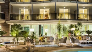 Eine Hotelhalle mit Pool, Liegestühlen und Topfpflanzen.