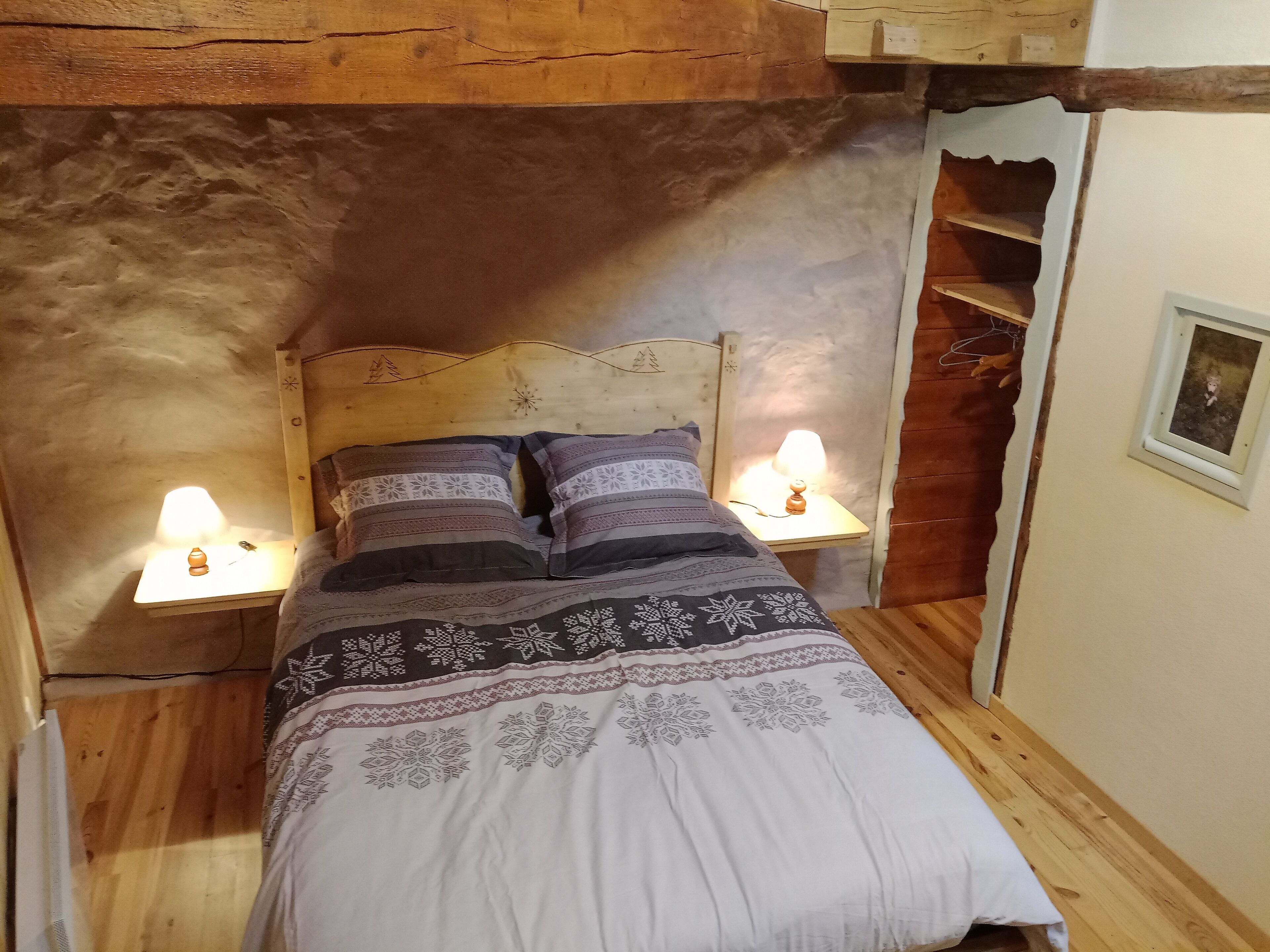 Un dormitorio acogedor con cabecera de madera, dos lámparas de noche y una cama con ropa de cama estampada.