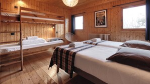 A wooden cabin with bunk beds, a fan, and a poster on the wall. - Chalet 10 pers, on the slopes, Mont Blanc view (St nicolas de veroce / st gervais les ba)