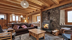 A cozy living room with wooden furniture, a stone fireplace, and a large window. - Chalet 10 pers, on the slopes, Mont Blanc view (St nicolas de veroce / st gervais les ba)