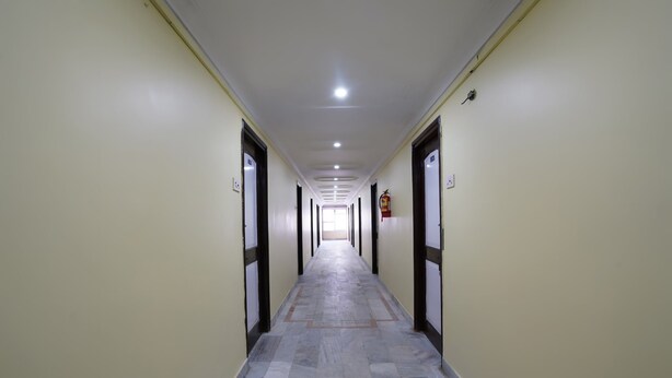 A long, narrow hallway with doors on both sides, a tiled floor, and a ceiling with recessed lighting. - OYO 49253 Raja Residency (Hyderabad)