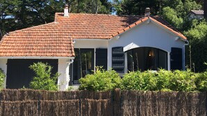 Una casa con techo de tejas, paredes exteriores blancas y un porche cubierto.
