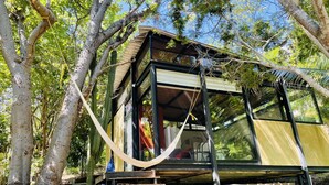 A treehouse with a glass enclosure, wooden deck, and a hammock. - Loft, Queen and single bed, kitchen-dining room-outside terrace (Salchi)