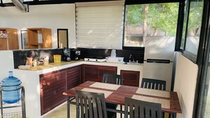 A compact kitchen with a dining area, a water dispenser, and a refrigerator. - Loft, Queen and single bed, kitchen-dining room-outside terrace (Salchi)