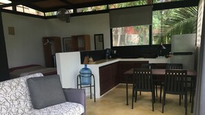 A compact living space with a sofa, dining table, and chairs, a kitchenette, and a water dispenser. - Loft, Queen and single bed, kitchen-dining room-outside terrace (Salchi)