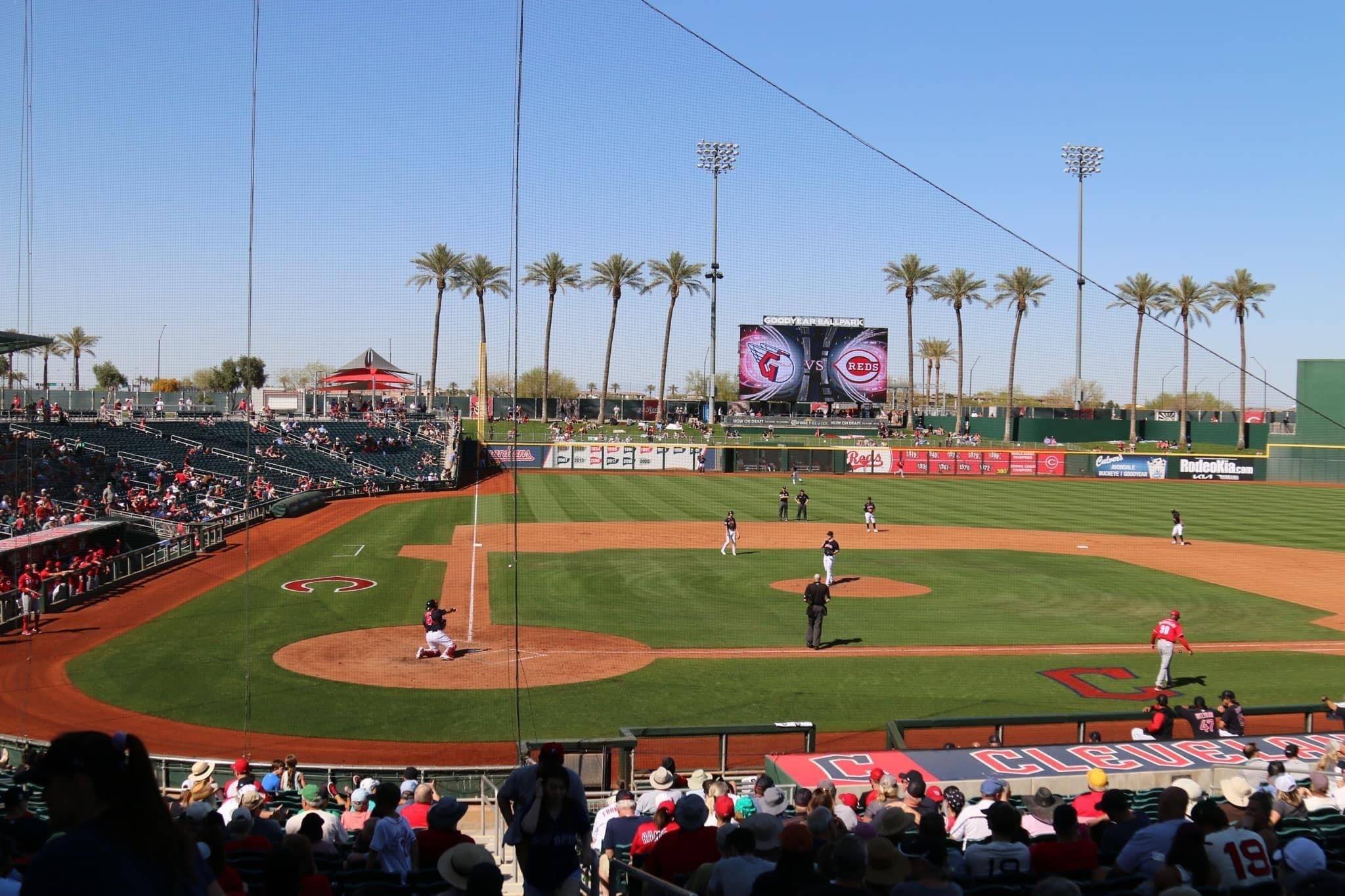 Un estadio de béisbol con una pantalla gigante mostrando un partido entre los Gigantes y los Rojos.