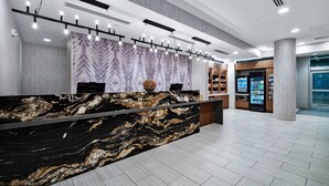 A modern reception area with a marble counter, a patterned wall, and a vending machine in the background. - SpringHill Suites by Marriott Phoenix Goodyear (Goodyear)