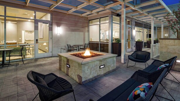 An outdoor patio with a fire pit, wicker chairs, and a glass-enclosed dining area. - SpringHill Suites by Marriott Phoenix Goodyear (Goodyear)