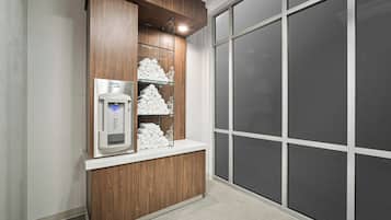 A hotel reception area with a water dispenser, neatly folded towels, and a large window with a view.