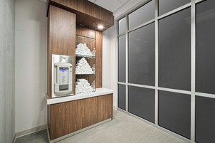A hotel reception area with a water dispenser, neatly folded towels, and a large window with a view.