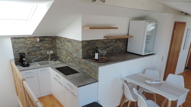 Una cocina compacta con protector de piedra, un refrigerador integrado y una zona de comedor con mesa y sillas.