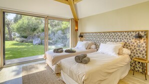 Une chambre avec deux lits, une grande fenêtre et une vue sur un jardin.