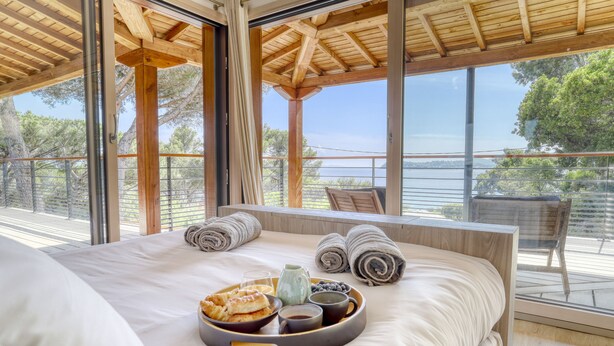 Une chambre avec un grand lit, un plateau avec des articles pour le petit-déjeuner et un balcon offrant une vue sur la mer.