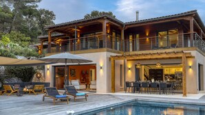 Une maison moderne à deux étages dotée d’une piscine, d’un espace salon extérieur et d’un coin repas.