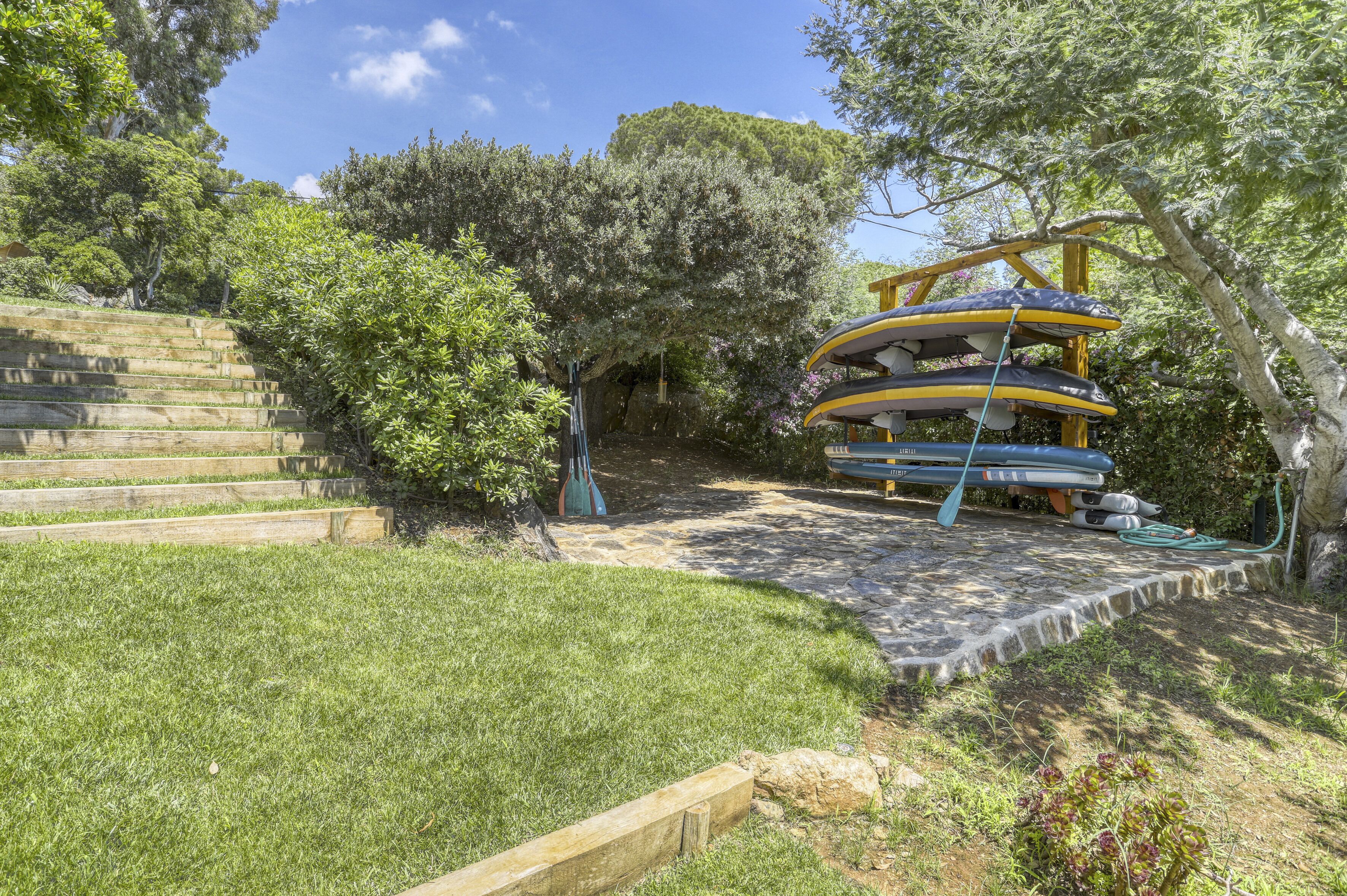 A stone staircase leading up to a wooden deck surrounded by lush greenery and trees.