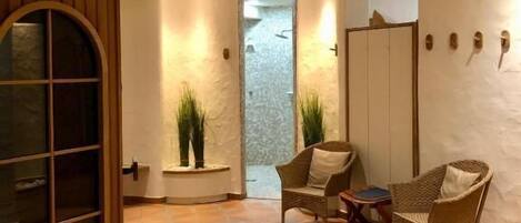 A room with a tiled floor, a wooden cabinet, two wicker chairs, and a small table.