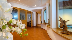 A hotel corridor with a view of a pool through large windows. - Hotel am Wasserfall (Lingen)