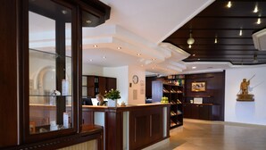A reception area with a wooden reception desk, a clock, and a statue on the wall. - Hotel am Wasserfall (Lingen)