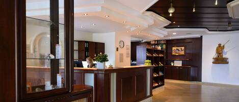 A reception area with a wooden reception desk, a clock, and a statue on the wall.