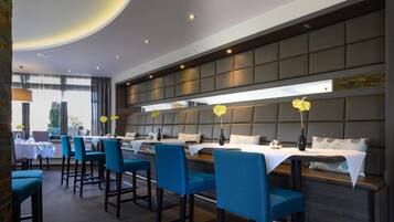 Un restaurante moderno con una barra larga y sillas tapizadas en azul.