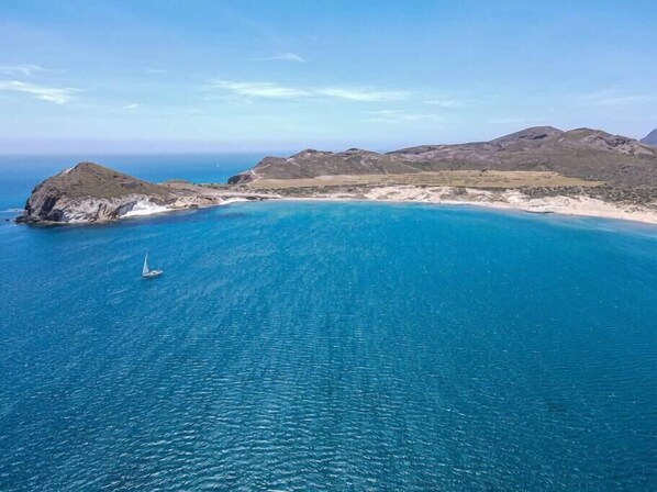 Overlooking the vast blue sea, this serene coastal landscape offers breathtaking views of the ocean and surrounding rocky outcrops.