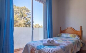 Relax in this serene bedroom with a comfortable bed and balcony overlooking the trees.