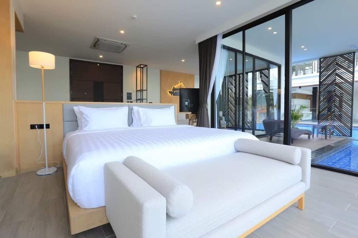 Une chambre d’hôtel moderne dotée d’un grand lit, d’une télévision à écran plat, d’une table de chevet et offrant une vue sur une piscine.
