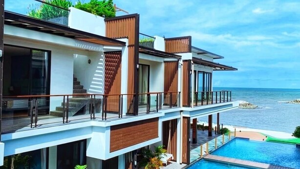 Ein modernes, mehrgeschossiges Gebäude mit Pool, großen Fenstern und Meerblick.