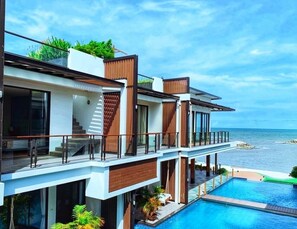 A modern multi-story building with a pool, large windows, and a view of the sea. - Klongwan Resort (Prachuap Khiri Khan)