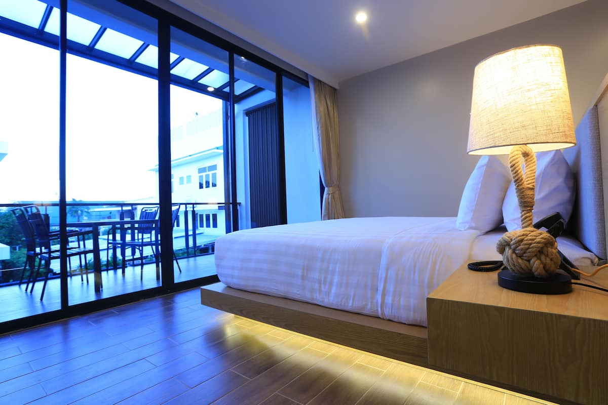 Une chambre d’hôtel avec un grand lit, une lampe de chevet et une vue sur l’extérieur grâce à de grandes fenêtres.
