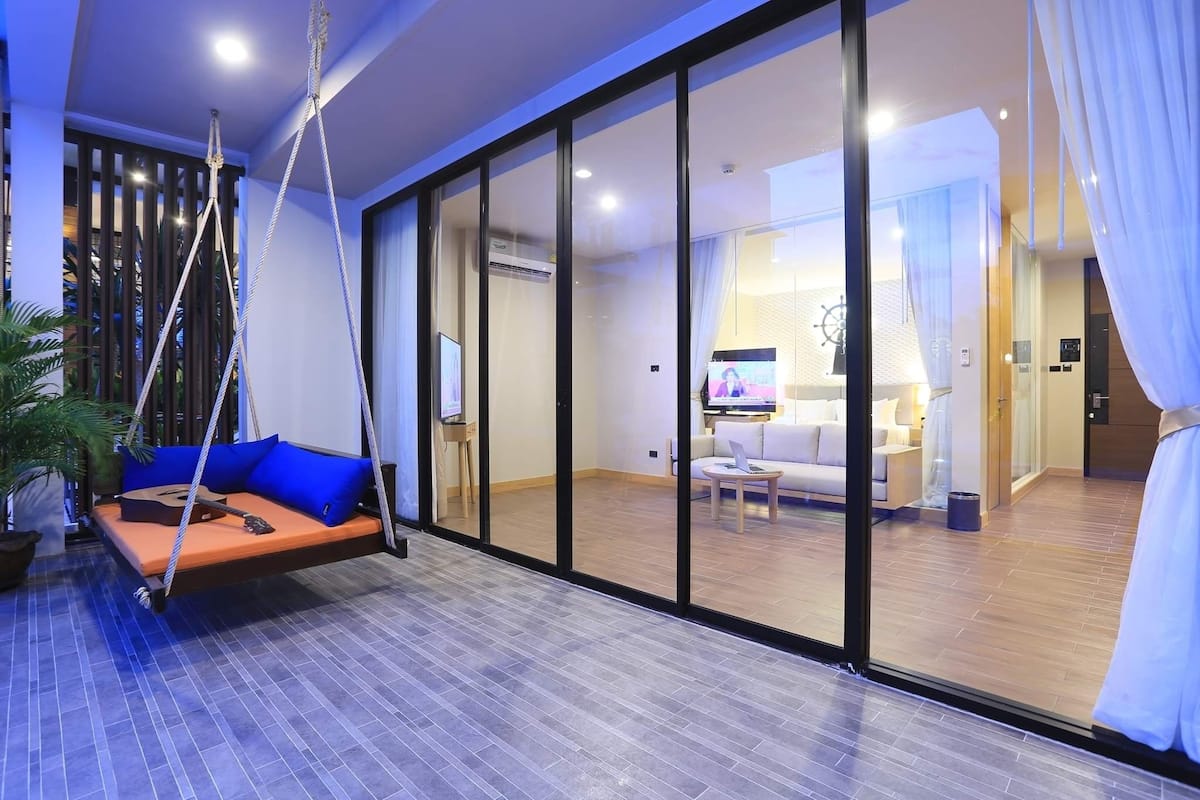 Un salon moderne avec un fauteuil suspendu, un canapé et un téléviseur en arrière-plan.